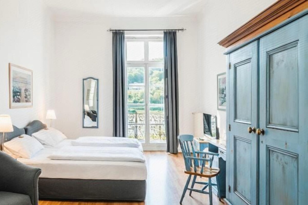 A hotel room with a bed, two bedside tables, a chair, a desk, and a wardrobe.