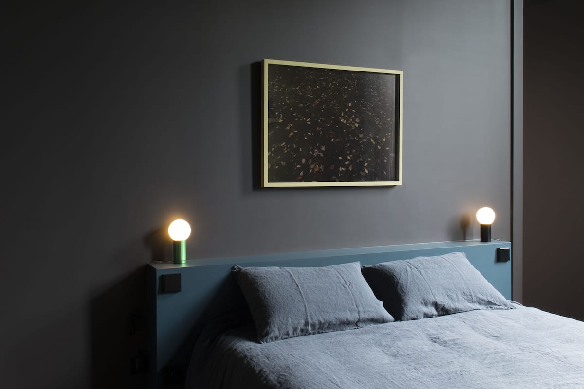 Un dormitorio con una cama, dos lámparas de noche y una obra de arte enmarcada en la pared.