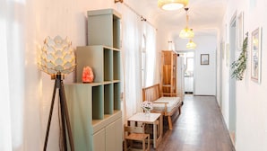 A hallway with a wooden bench, a small table with a vase, and a tripod lamp. - Paydos Pansiyon (Kas)