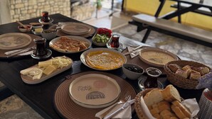 A table set with various dishes, including a plate of cheese, a bowl of olives, and a plate of bread. - Paydos Pansiyon (Kas)