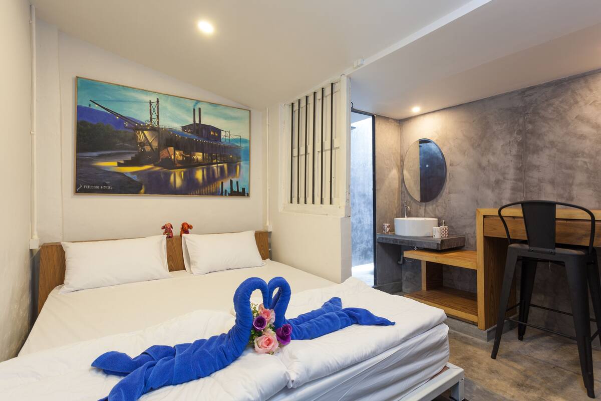 Una habitación de hotel con cama, un cuadro en la pared, escritorio y baño.
