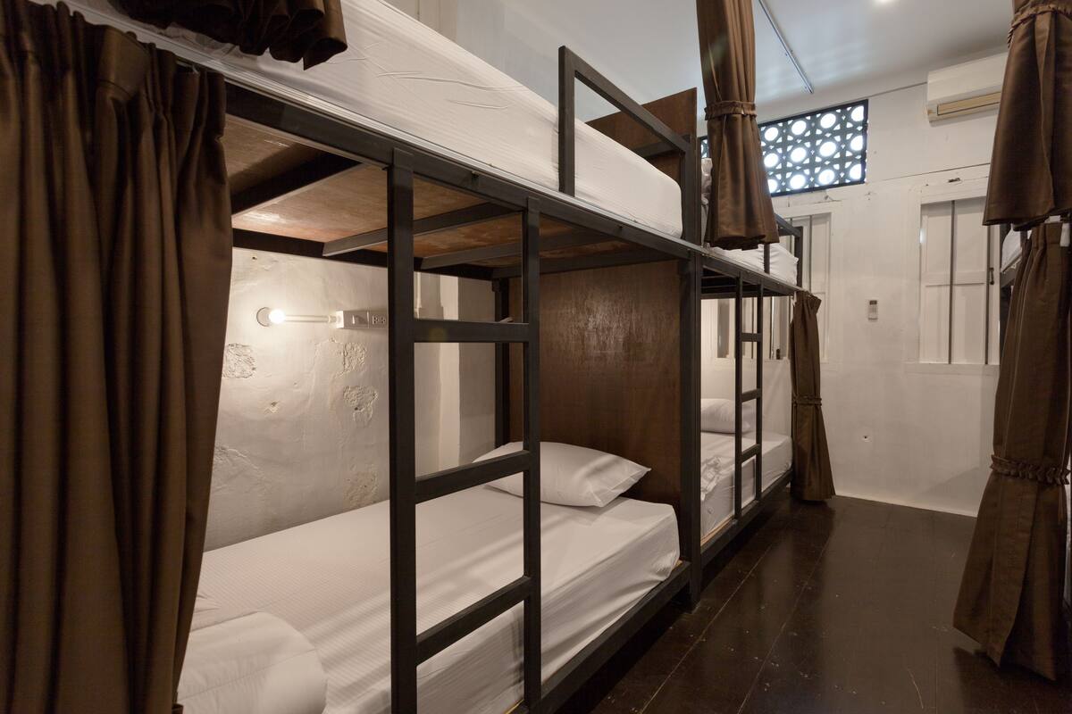 Dormitorio con literas, ventana, cortinas y suelo de madera.