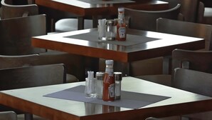 A restaurant with multiple tables, each equipped with condiments and a menu. - Lagos Hotel (Nairobi)
