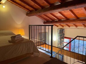 A bedroom with a bed, a nightstand, a lamp, and a view of the outside through a window. - Borgo La Capraia (Castelfranco Piandisco)