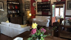A cozy living room with a fireplace, a bookshelf, a dining area, and a view of the outdoors. - Borgo La Capraia (Castelfranco Piandisco)