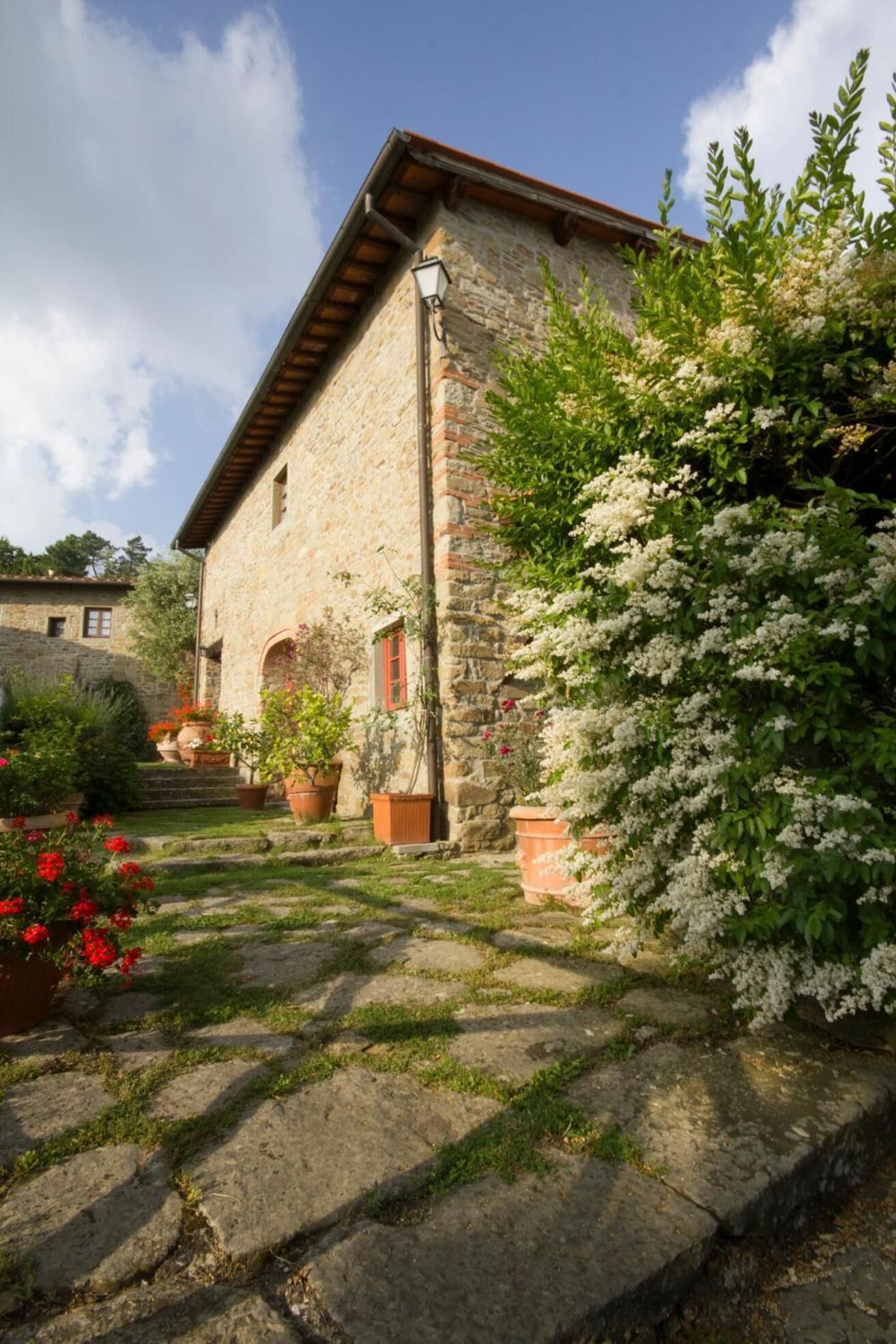 A stone building with a sloped roof, a small porch with steps, and potted plants.