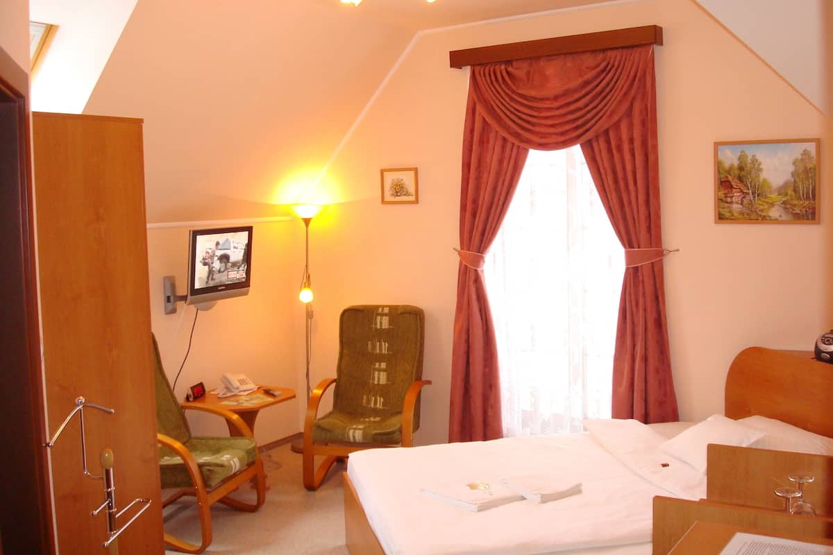 Ein Hotelzimmer mit einem Bett, einem Schreibtisch, einem Sessel, einer Lampe und einem Bild an der Wand.