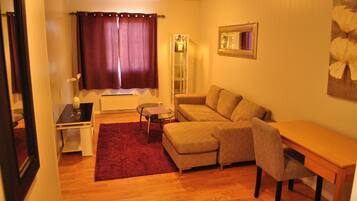 A cozy living room with a sofa, a small table, and a red rug.