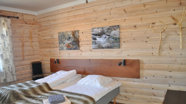 Una habitación con paneles de madera, una cama, dos cuadros y un manto de piel.