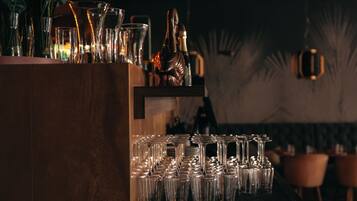 A bar area with a wooden counter and multiple glasses and bottles.