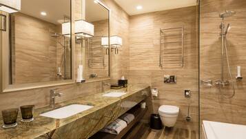 A modern bathroom with two sinks, a large mirror, a shower, and a toilet.