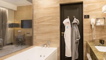 Un baño moderno con una bañera grande, un tocador con encimera de mármol y un secador de pelo montado en la pared.