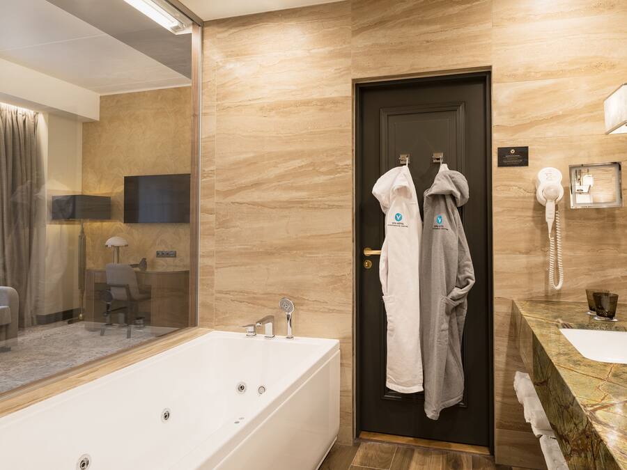 Un baño moderno con una bañera grande, un tocador con encimera de mármol y un secador de pelo montado en la pared.