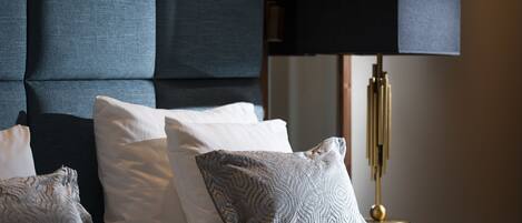 A bed with multiple pillows, a dark headboard, and a bedside lamp.