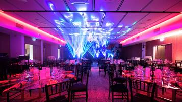 A banquet hall with tables set for dining, equipped with glassware and napkins.