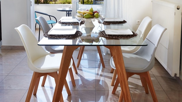 A dining area with a glass table, white chairs, and a view of the sea. - Dream Villa (Chania)