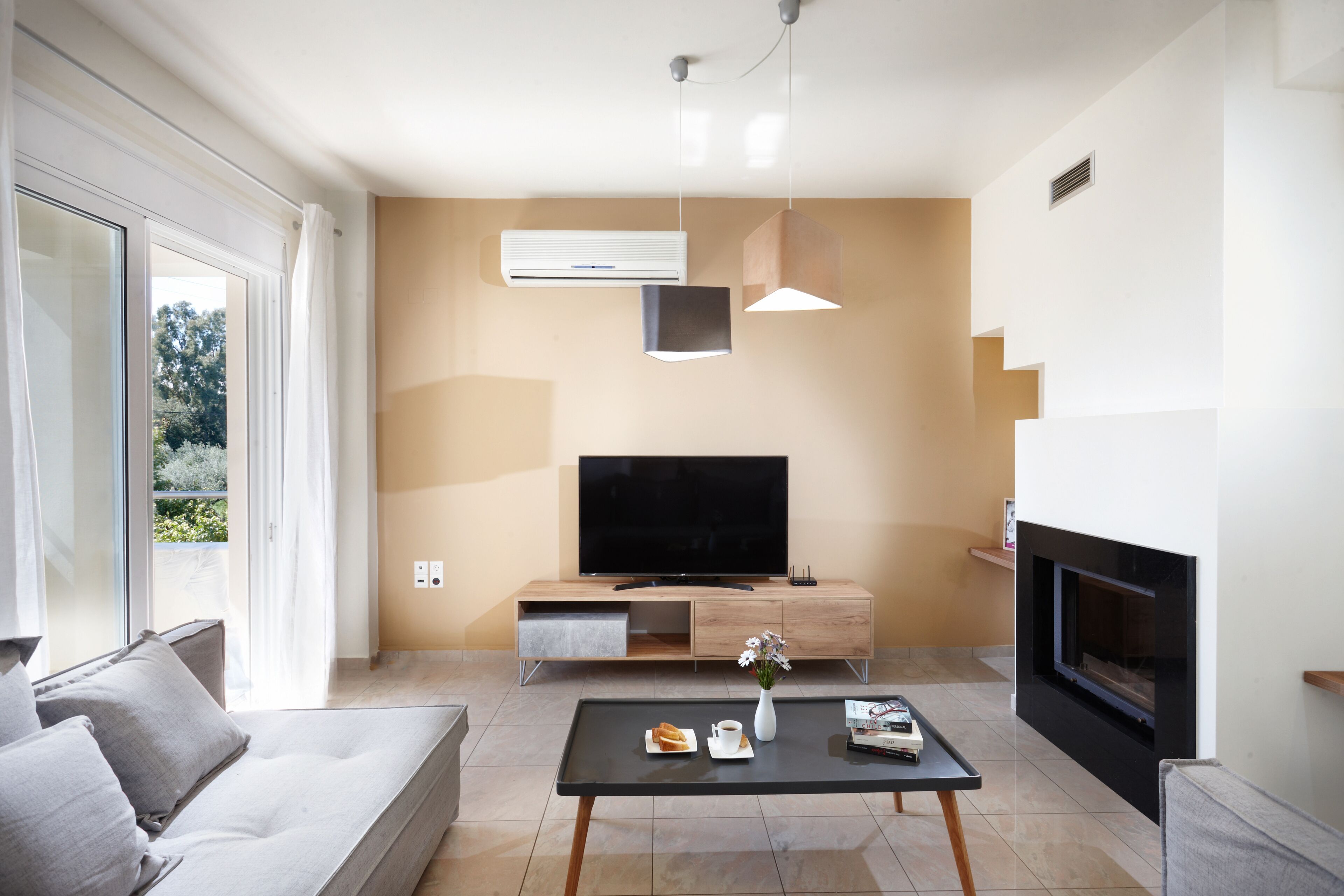 A modern living room with a sofa, coffee table, TV, and fireplace.