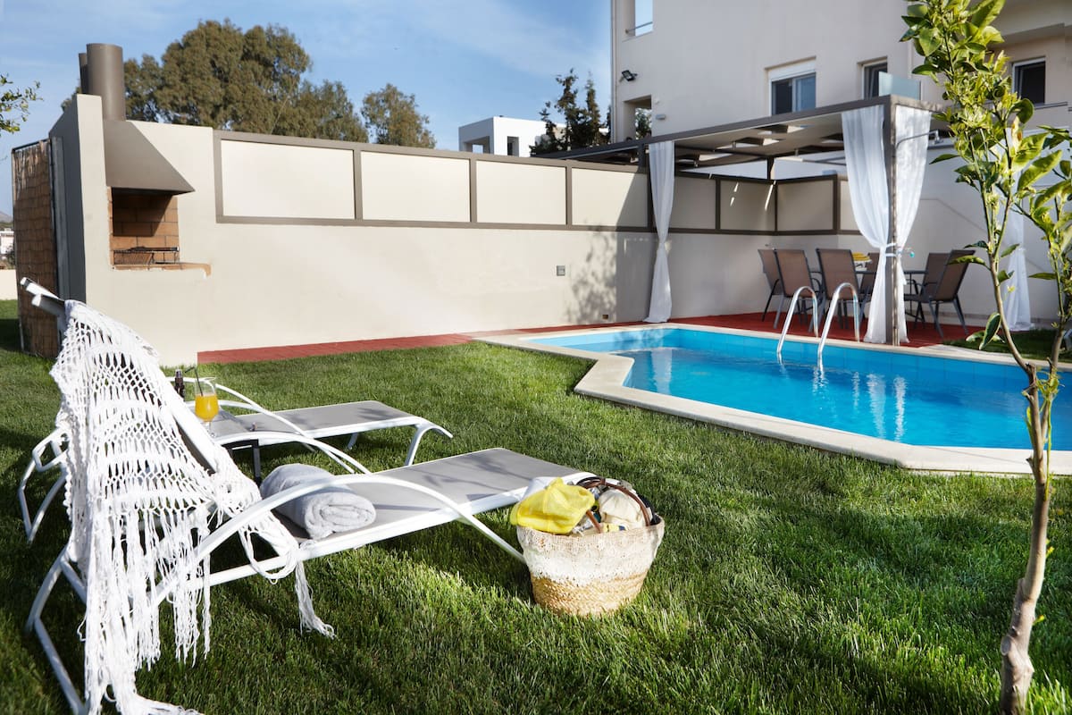 A poolside area with lounge chairs, a small pool, and a barbecue grill.