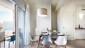 A modern dining area with a glass table, four chairs, and a pendant light. - Dream Villa (Chania)