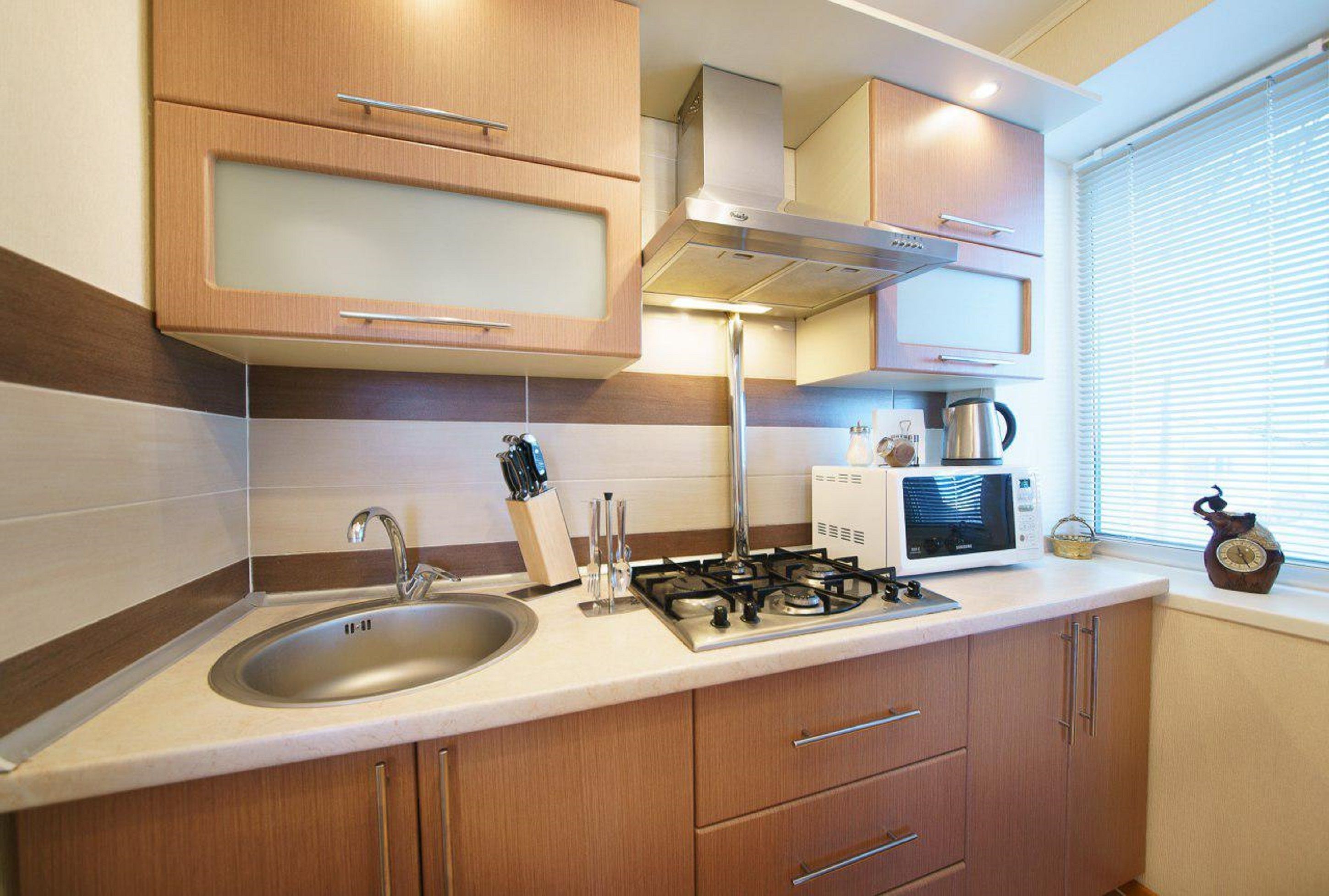 A modern kitchen with a stainless steel sink, gas stove, and wooden cabinets.