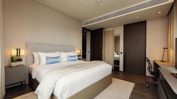 A modern bedroom with a large bed, bedside tables, a desk, and a chair.