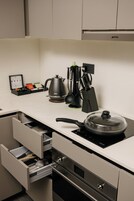 A modern kitchen with a built-in stove, a kettle, and various utensils.