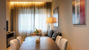 A modern dining area with a rectangular table, six chairs, a lamp, and a television on a stand.