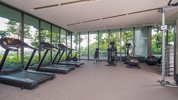 Un gimnasio moderno con cintas de correr, máquinas de pesas y pelotas de ejercicio.