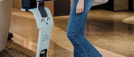 A woman interacting with a self-service kiosk in a modern lobby with artwork on the walls.