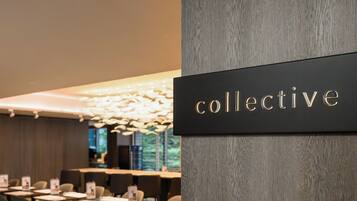 A modern dining area with a 'collective' sign, tables, chairs, and ambient lighting.