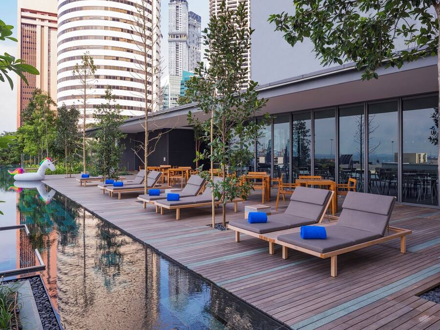 Un área de piscina en la azotea con sillones reclinables y una pequeña decoración de unicornio inflable.