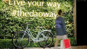 Una persona caminando frente a un muro con una bicicleta y el texto "Live your way #thedaoway".