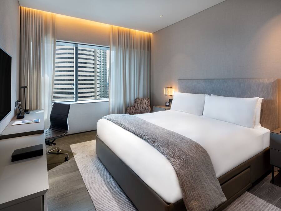 Una habitación de hotel moderna con una cama grande, un escritorio, una silla y un televisor.