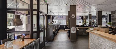 Interior de restaurante moderno com tetos altos, painéis de teto listrados e um balcão central de atendimento.