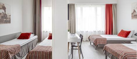 A hotel room with four single beds, a dining table, and a chair.
