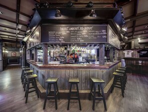 A bar area with stools, a menu board, and a variety of bottles and glasses. - Hotel Seurahuone (Riihimaki)