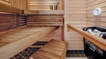 A sauna with wooden benches, a small table, and a hot tub.