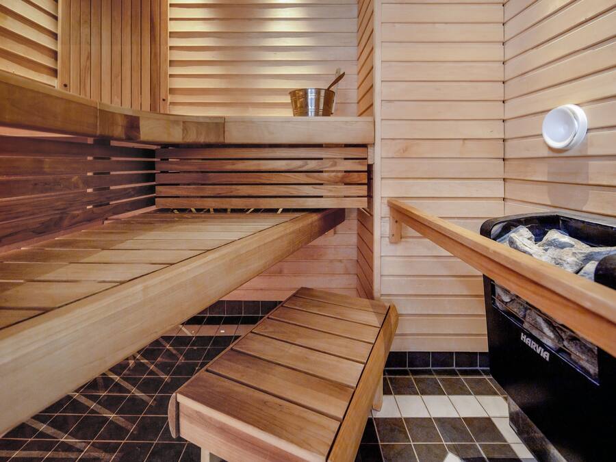 A sauna with wooden benches, a small table, and a hot tub.