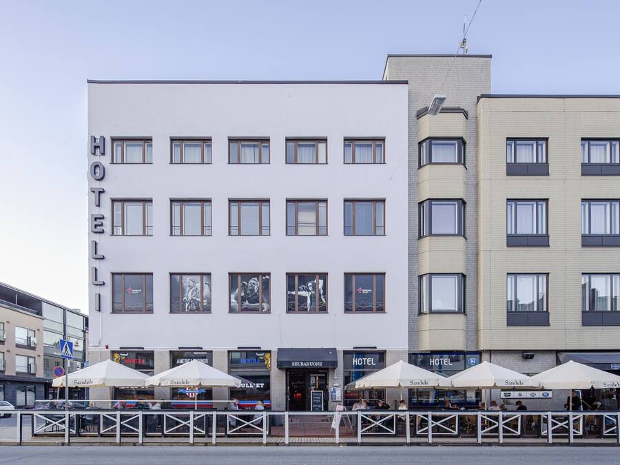 A hotel with multiple floors, outdoor seating with umbrellas, and a visible entrance.