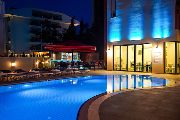 Una piscina al aire libre, sombrillas, sillones reclinables de piscina