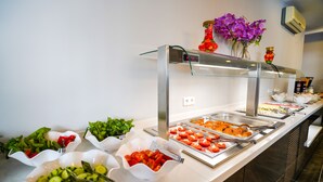 Un bufé con diversas opciones de comida, incluyendo ensaladas, verduras y carnes.