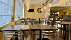 A spacious dining area with multiple tables and chairs, large windows, and hanging pendant lights. - Hotel Alverì (Mestre)