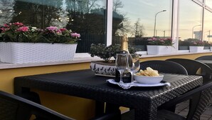 An outdoor dining area with a table set for two, featuring a bottle of champagne, a bowl of chips, and a glass. - Hotel Alverì (Mestre)