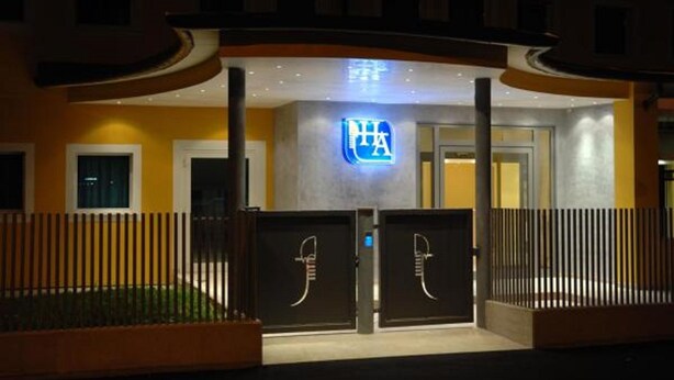 A hotel entrance with a prominent illuminated logo, a gated driveway, and a modern architectural design. - Hotel Alverì (Mestre)