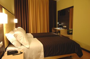 A hotel room with two beds, a desk with a computer, a telephone, and a mirror.