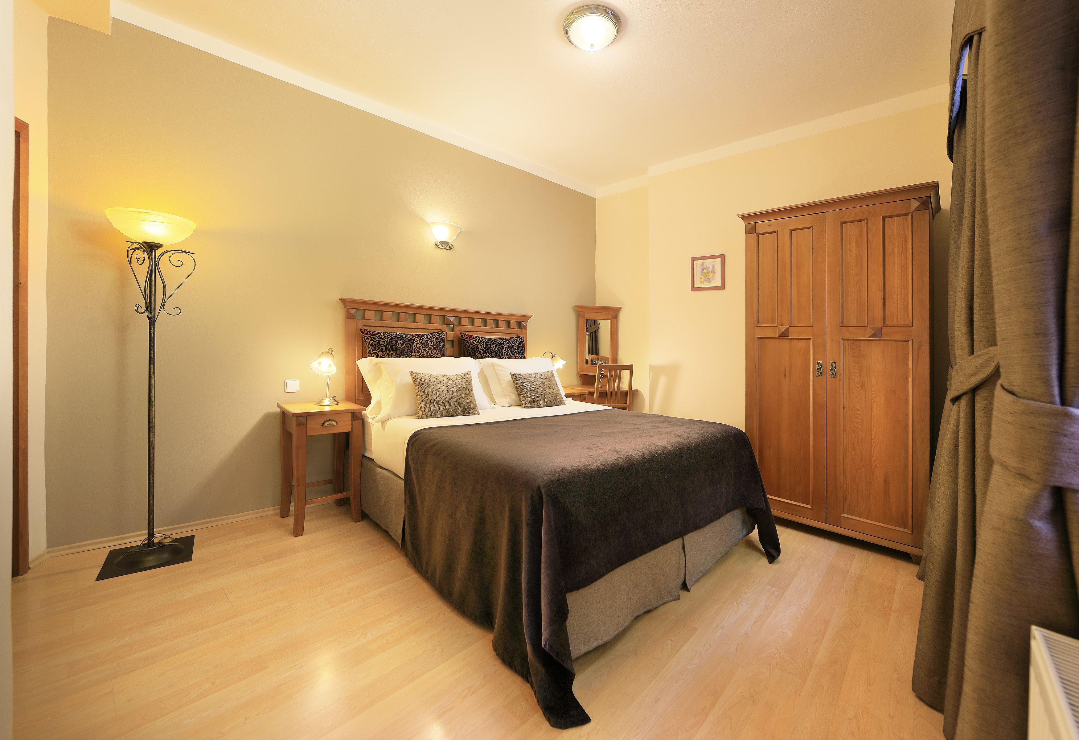 Un dormitorio con una cama, lámparas de noche, un armario y una lámpara de pie.
