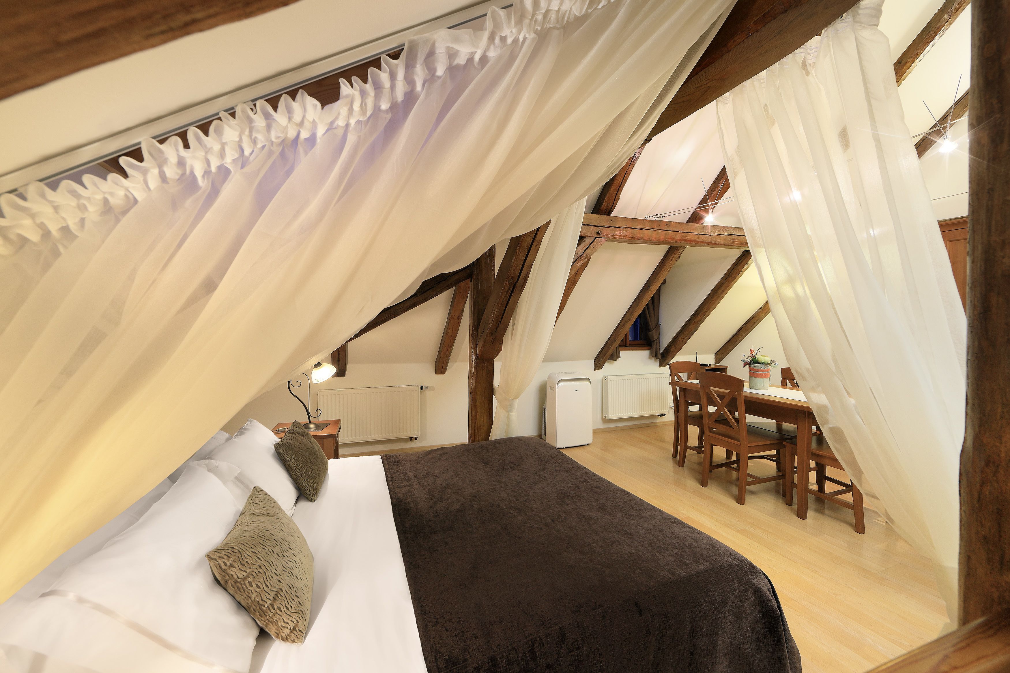 A cozy attic bedroom with a bed, a desk, and a chair.