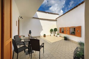 A patio with a table and chairs, potted plants, and a tiled floor. - Castle View Apartments (Cesky Krumlov)