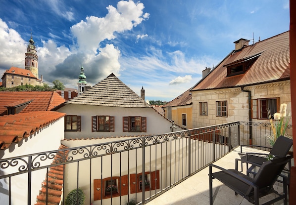 A courtyard with a balcony, a tiled roof, and a building with a tower. - Castle View Apartments (Cesky Krumlov)