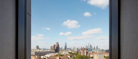 A cityscape through a window with a clear sky, featuring a mix of modern and traditional buildings.